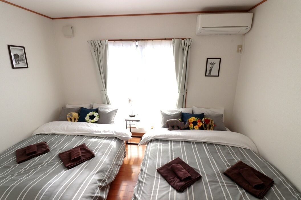 A hotel room with two beds, striped bedding, and a view of the outdoors.