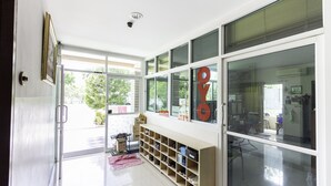 A modern interior with a glass door leading to an outdoor area, a wooden bench with storage, and a visible kitchen area.
