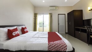 A hotel room with a bed, a TV, a wardrobe, and a balcony with curtains.