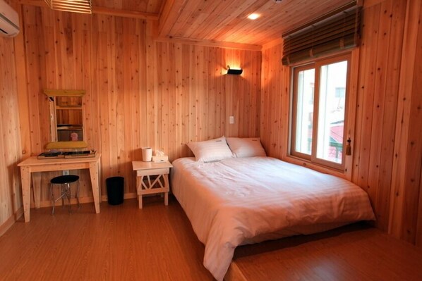 A wooden room with a bed, a desk, and a window.