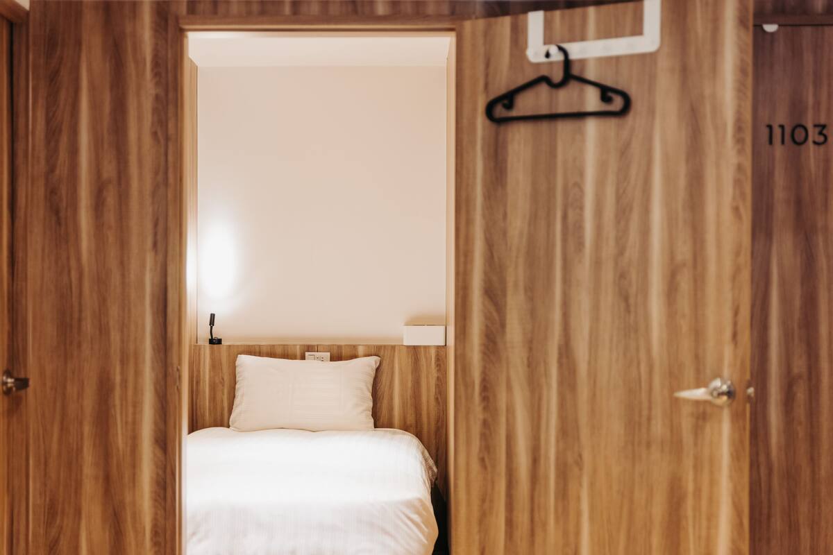 Ein Zimmer mit Holzboden, einem Bett, einer Pendelleuchte und der Nummer '1103' an der Wand.