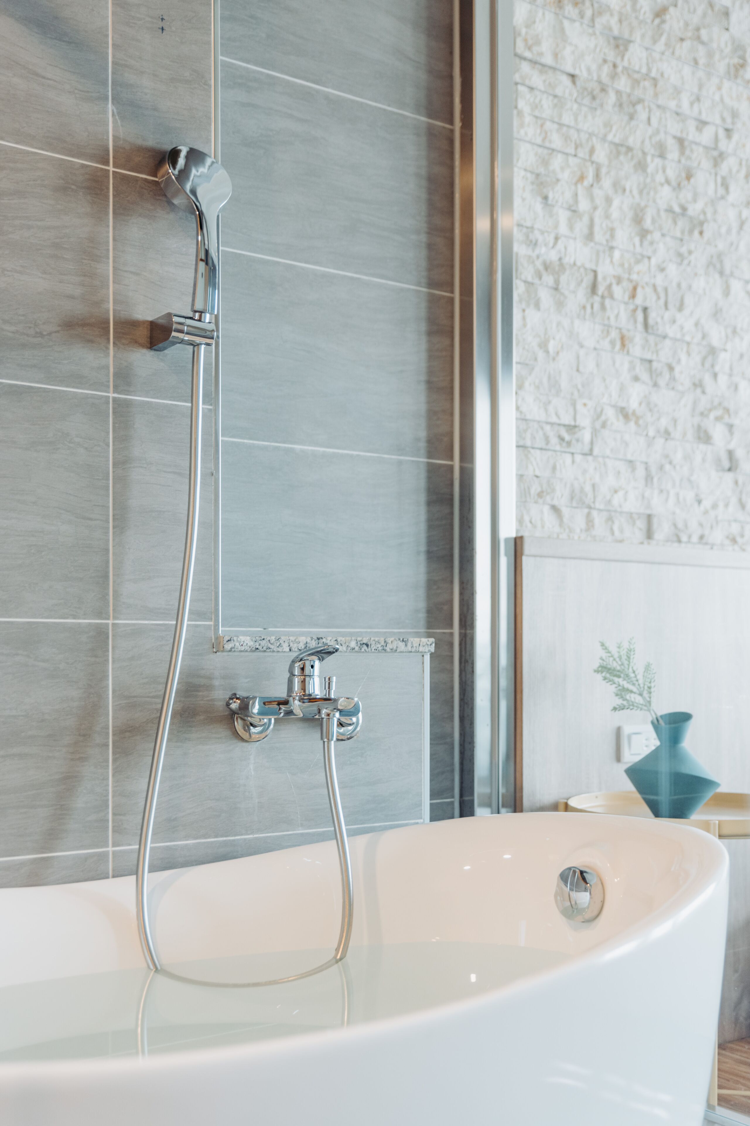 Un baño moderno con una bañera independiente, un cabezal de ducha manual y un área de ducha con mampara de vidrio.