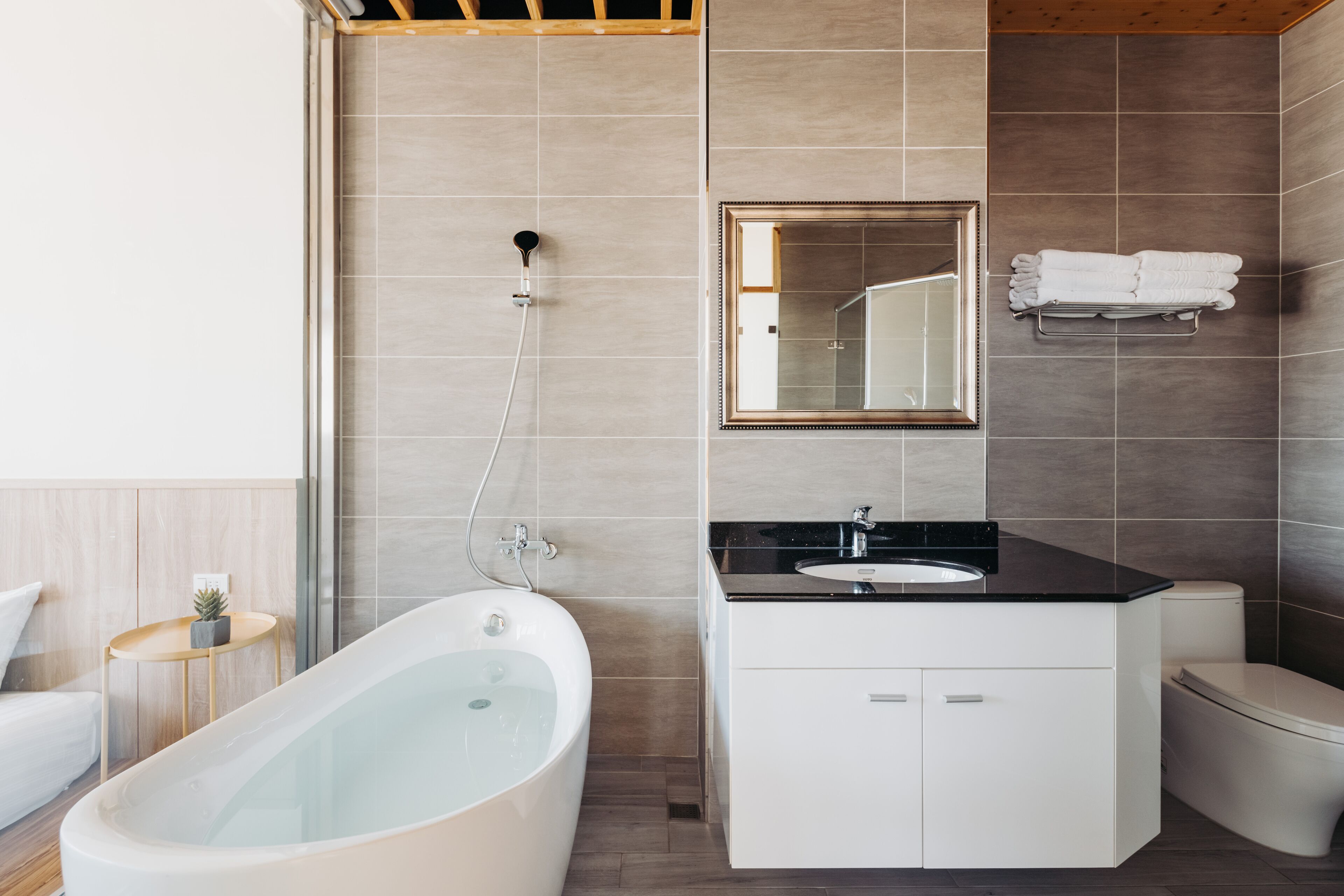 A modern bathroom with a freestanding bathtub, a vanity with a sink, a toilet, and a mirror above the vanity.