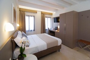 Une chambre d’hôtel avec un lit, un bureau, une télévision et une armoire.