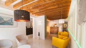A modern interior with a wooden ceiling, a dining area with yellow chairs, and a kitchen in the background. - Leone (Venice)