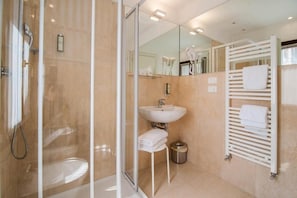 A modern bathroom with a glass shower enclosure, a sink, and a towel rack. - Leone (Venice)