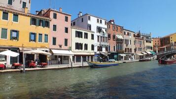 A canal with colorful buildings, a boat, and outdoor seating along the water's edge.