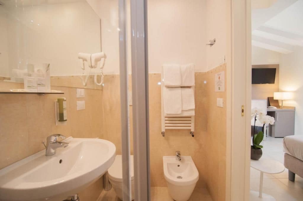 A modern bathroom with a sink, bidet, and towel rack.