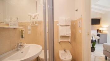 A modern bathroom with a sink, bidet, and towel rack.