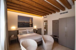 A bedroom with a bed, two bedside tables, a nightstand, a wardrobe, and a painting of a lighthouse on the wall. - Leone (Venice)