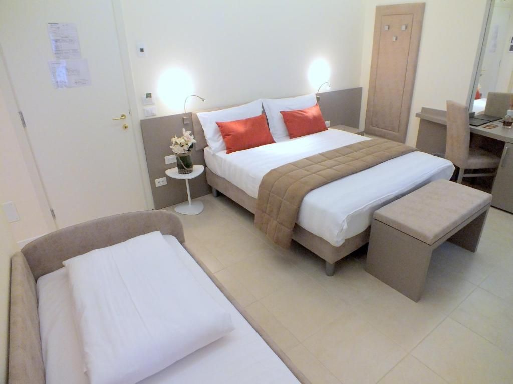 Een hotelkamer met een bed, nachtkastjes, een bureau en een stoel.