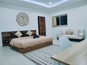 Een slaapkamer met een bed, een bank, een decoratief kunstwerk en een raam met gordijnen.