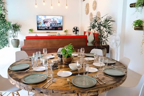 Een eetgedeelte met een ronde houten tafel, gedekt voor een maaltijd, omringd door witte stoelen.