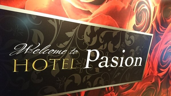 Un letrero de bienvenida para HOTEL Passion con un fondo floral.