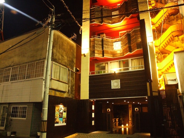 A multi-story building with a traditional architectural style, featuring wooden balconies and a central entrance with a small shrine.