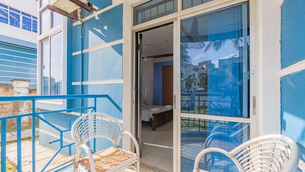 Un balcone con sedie in rattan bianco e ringhiera blu.