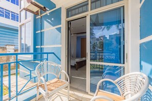 Ein Balkon mit weißen Korbstühlen und einem blauen Geländer.