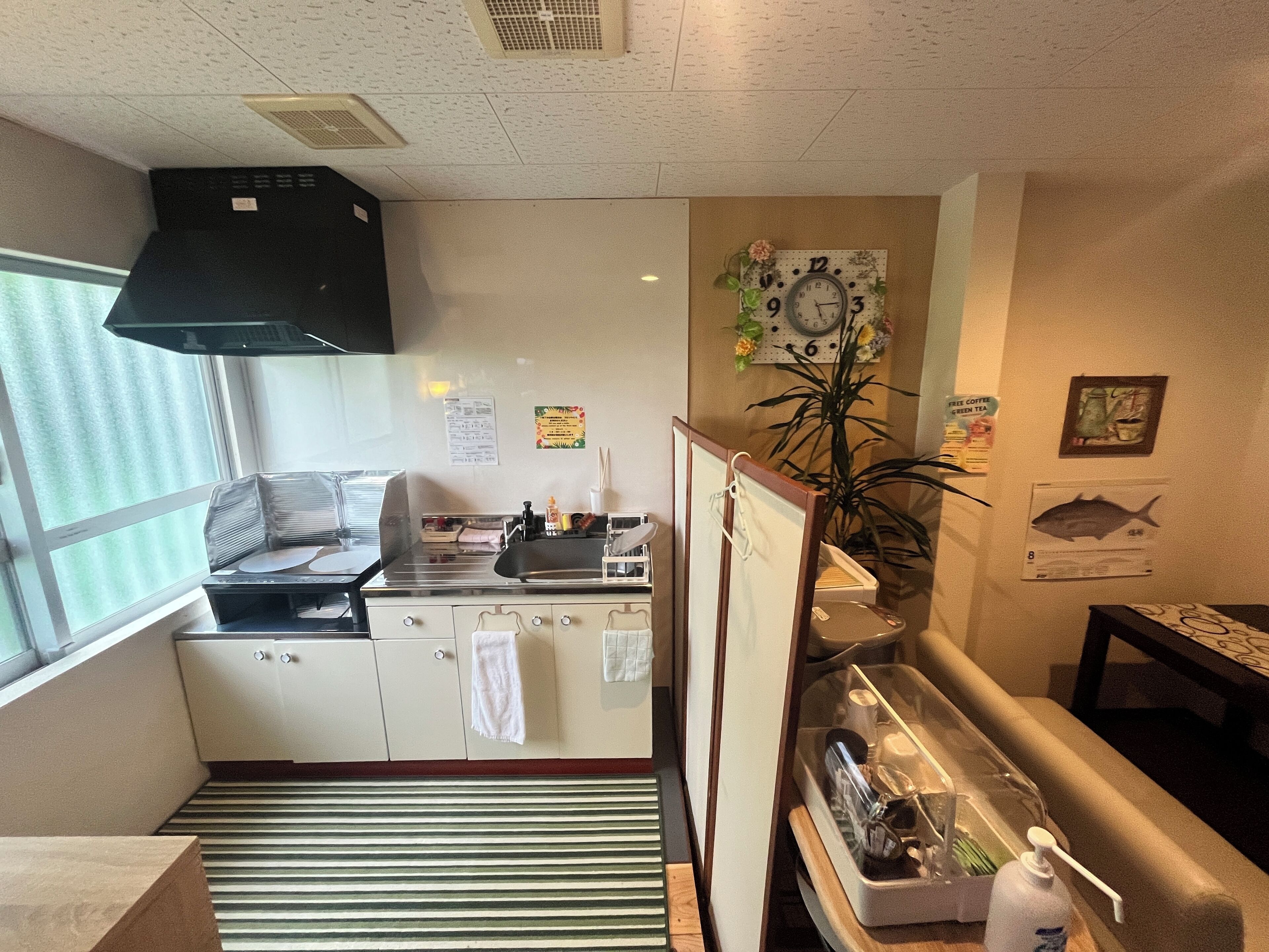 A compact kitchen with a stove, sink, and a clock on the wall.