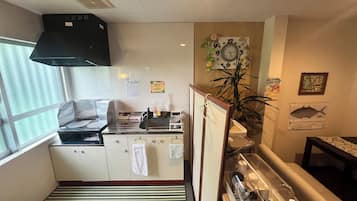 A compact kitchen with a stove, sink, and a clock on the wall.