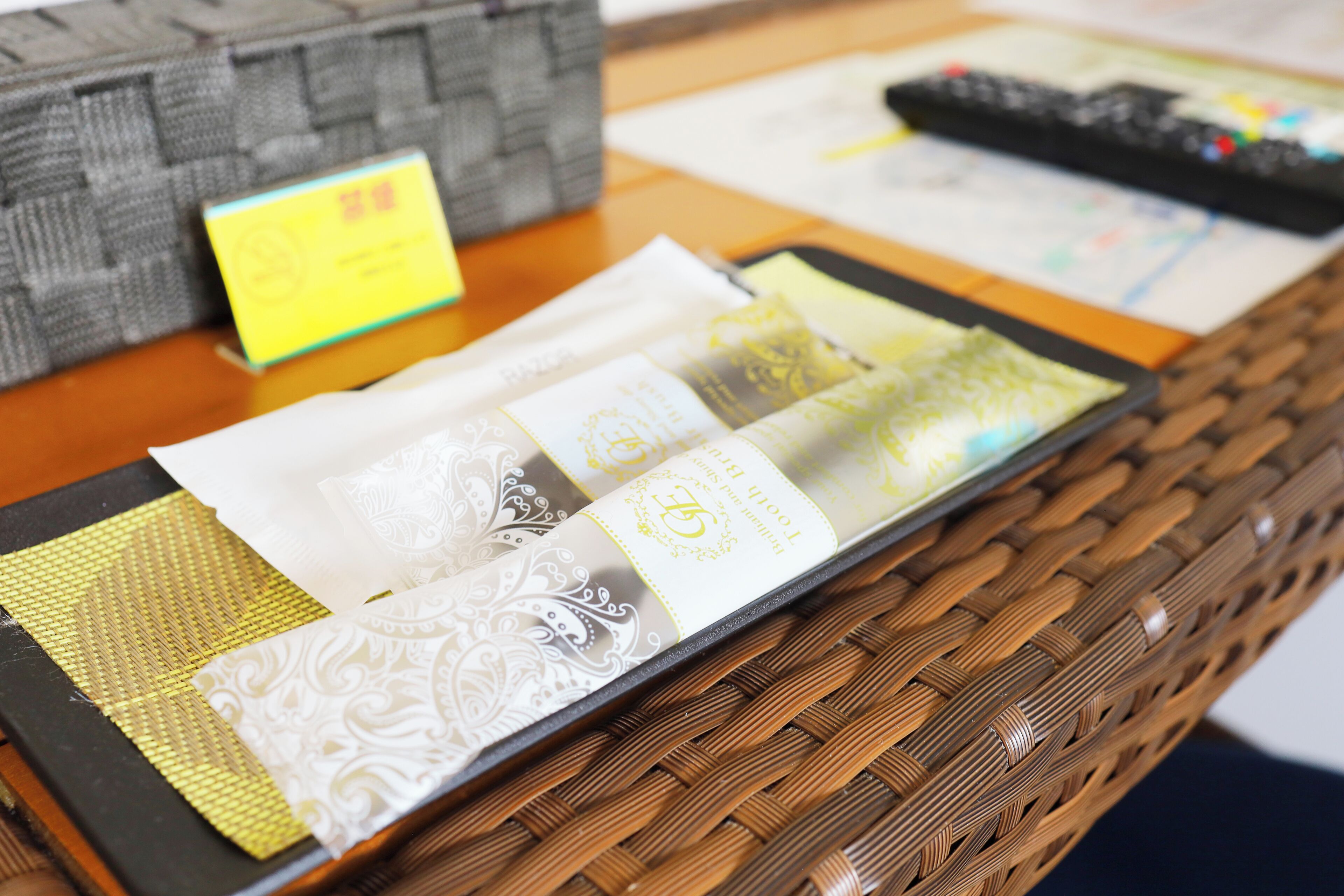 A check-in counter with a basket containing a yellow card, a black remote control, and a booklet.