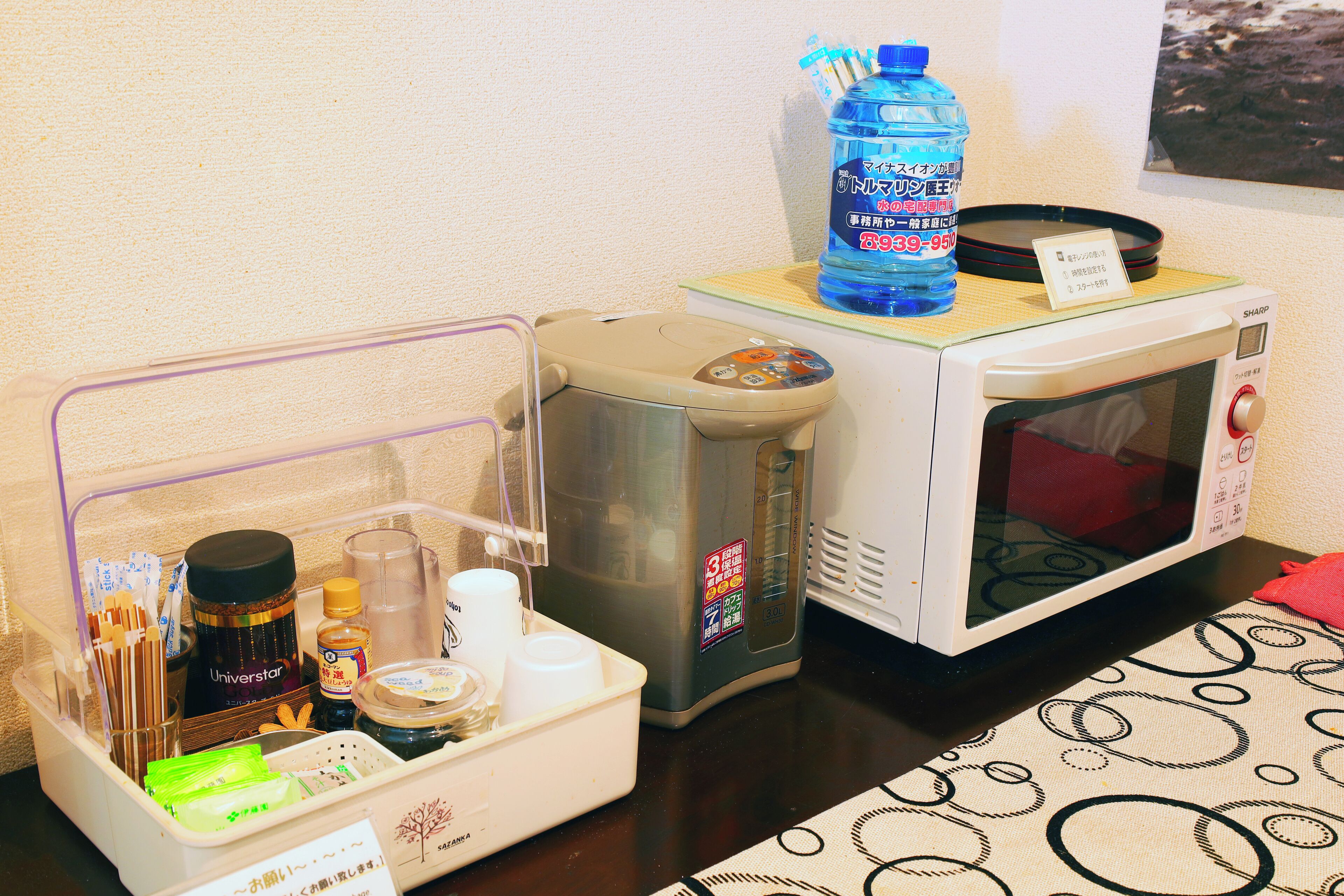 Una kitchenette equipada con cafetera, dispensador de agua y microondas.