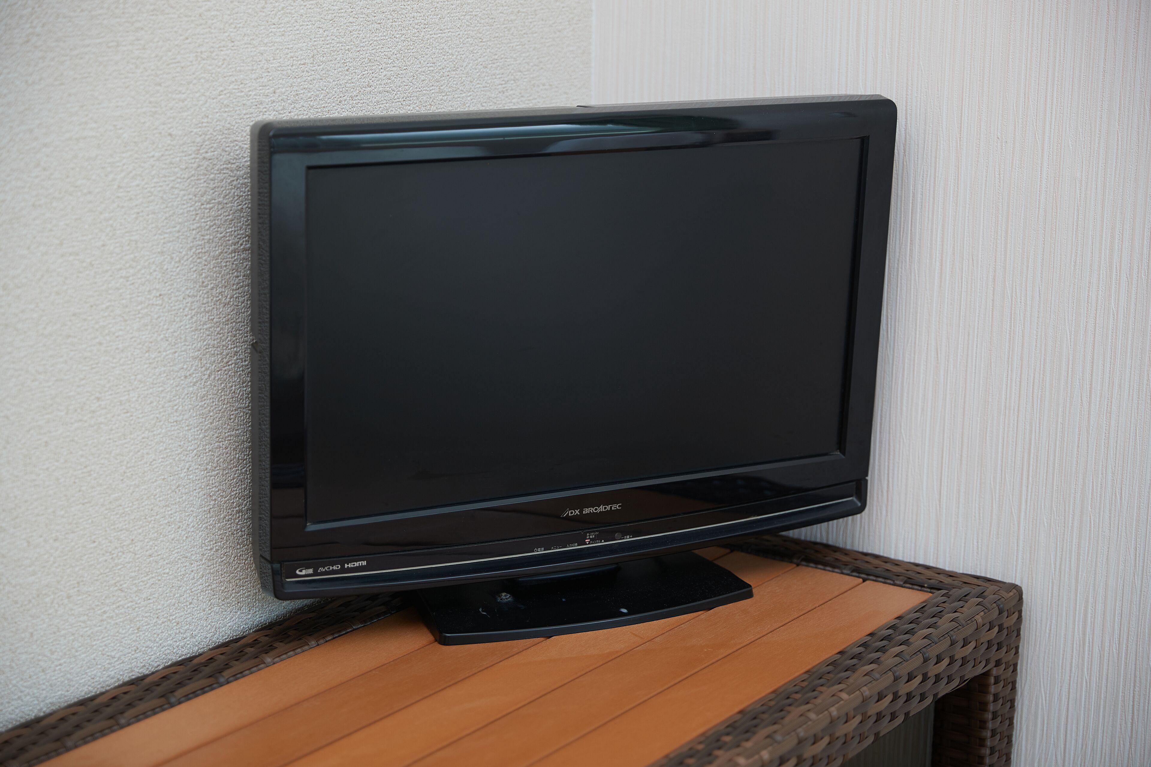 A flat-screen TV on a wooden table against a textured wall.
