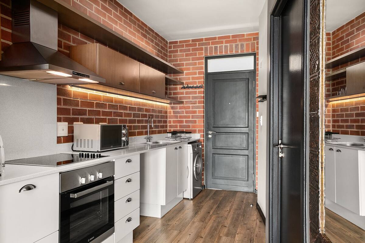 Una cocina moderna con armarios blancos, una campana extractora de acero inoxidable, un microondas y un horno empotrado.