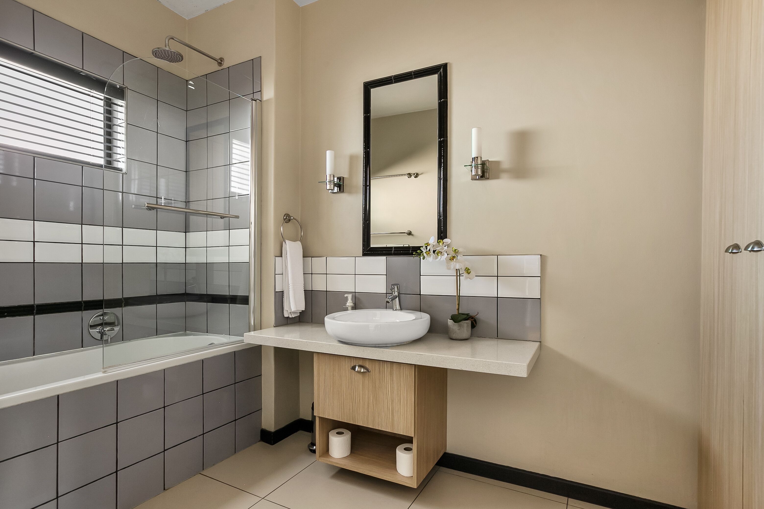 A modern bathroom with a bathtub, a sink, and a mirror.