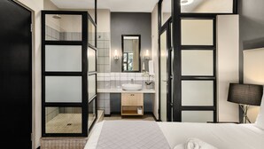 A modern hotel bathroom with a large mirror, a white sink, and a separate shower area. - Easy Stay - The Vantage (Johannesburg)
