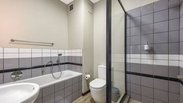 Un baño con bañera, inodoro y zona de ducha.