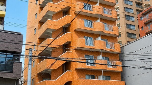 A multi-story building with a brick facade, balconies, and a ground-level entrance. - Yado gh (Sapporo)