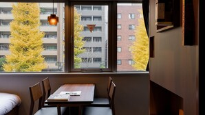 A room with a dining table, chairs, a window with autumn foliage, and a hanging light fixture. - COCOSHUKU Shinjuku-Hanazono (Tokyo)