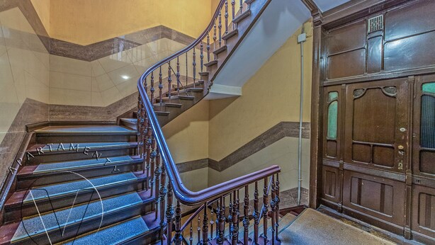 Un magnifique escalier avec des rampes richement décorées et une porte en bois dotée de panneaux de verre.