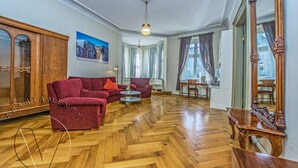 Un salon spacieux doté d’un parquet en bois à motifs de chevron, de deux canapés rouges, d’un meuble en bois et d’un grand miroir.