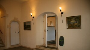 A hallway with a staircase, a door, a wall-mounted clock, and a framed painting. - Ferienwohnung im Pfarrhaus Maxen (Mueglitztal)