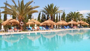 A pool area with thatched umbrellas and palm trees, surrounded by lounge chairs. - Sun Holiday Beach hôtel (Nabeul)