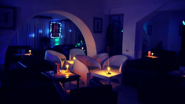 A dimly lit room with a modern, curved ceiling and a seating area with white chairs and tables. - Sun Holiday Beach hôtel (Nabeul)