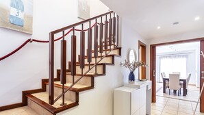 A staircase with wooden steps and metal railings, leading to a dining area with a table and chairs.