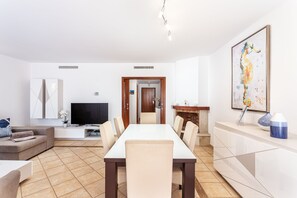 Ein modernes Wohnzimmer mit einer Couch, einem Fernseher und einem Esstisch mit Stühlen.