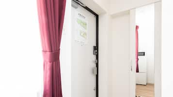 A hotel room with a closed door, a pair of slippers on the floor, and a tiled floor.