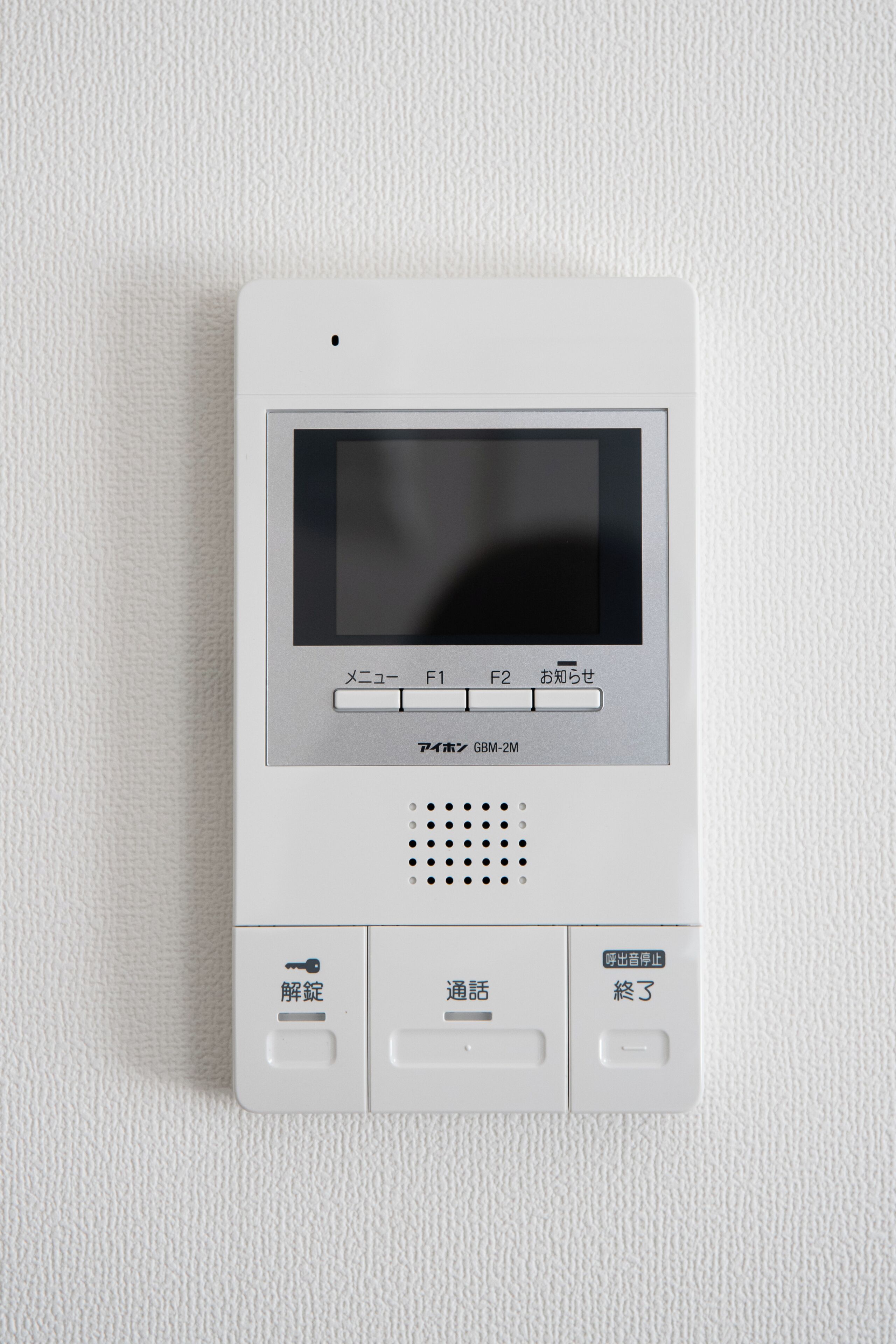 A white intercom system with a screen and buttons labeled in Japanese.