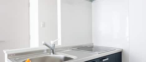 A modern kitchen with dark cabinets, a stainless steel sink, and a built-in oven.