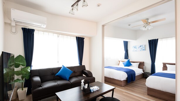Une chambre d’hôtel moderne équipée d’un canapé, de deux lits, d’une table basse et d’un appareil de climatisation.