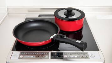Una cocina con una sartén roja y una olla roja sobre una placa de inducción.