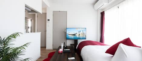Una habitación de hotel moderna con cama, televisión, escritorio y una silla roja.