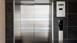Un ascenseur moderne avec une finition métallique, un panneau de commande doté d’un écran numérique et un clavier.