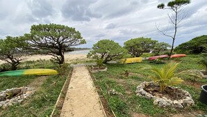 A pathway leading to a beach with trees and kayaks. - Beach Lodge 2 & Private Beach (Onna)
