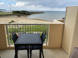 A balcony with a table and chairs, overlooking a beach and ocean. - Beach Lodge 2 & Private Beach (Onna)