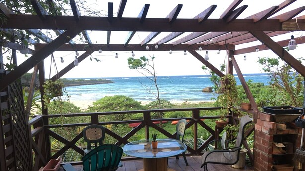 A covered outdoor seating area with a view of the ocean. - Beach Lodge 1 & Private Beach (Onna)