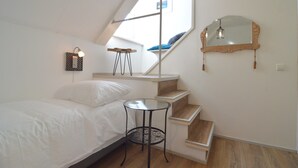 A bedroom with a bed, a small round table, a mirror, and a staircase. - Spacious Holiday Home in Rekken With Hot Tub (Rekken)